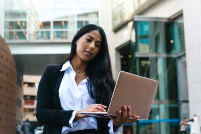 elegant latina businesswoman consulting financial operations on her laptop on the street.