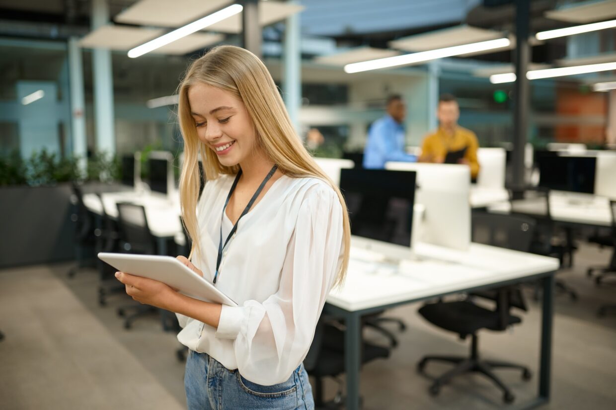 Smiling female manager holds laptop, IT office