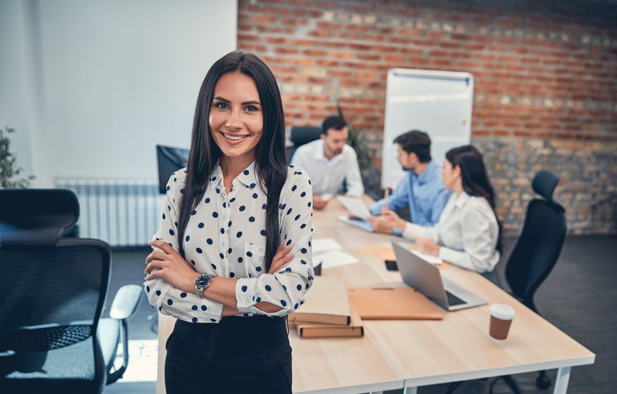 Smiling female manager with folded hands indoors