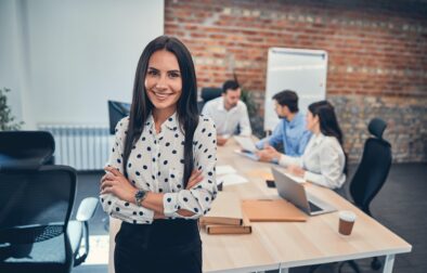 Smiling female manager with folded hands indoors