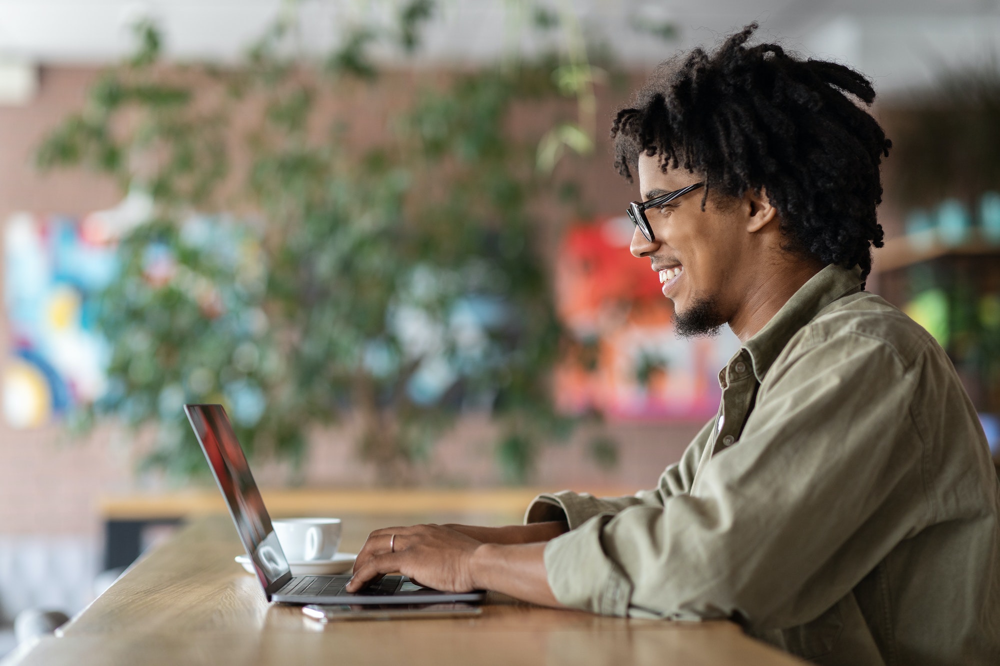 Black Blogger Guy Using Laptop At Cafe, Posting Content In Social Networks