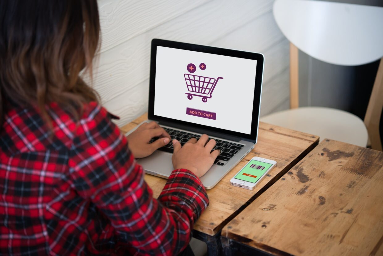 Online shopping website on laptop screen with female hands typing. Freedom shopping e-commerce.